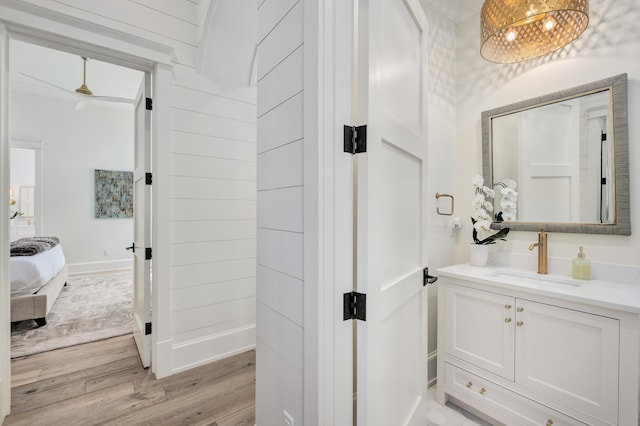 ensuite bathroom with baseboards, ensuite bathroom, wood finished floors, vanity, and a ceiling fan