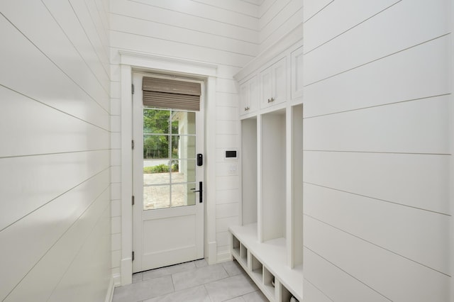 mudroom with light tile patterned floors and wood walls