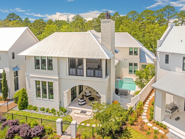 rear view of property with a gate, a fenced front yard, a chimney, and a patio area