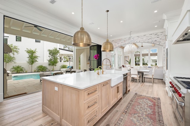 kitchen featuring ornamental molding, light brown cabinets, a sink, light wood finished floors, and custom exhaust hood