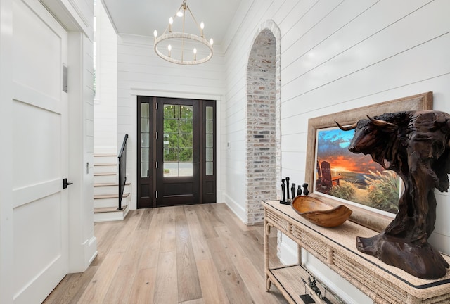 foyer with an inviting chandelier, stairway, and light wood-type flooring