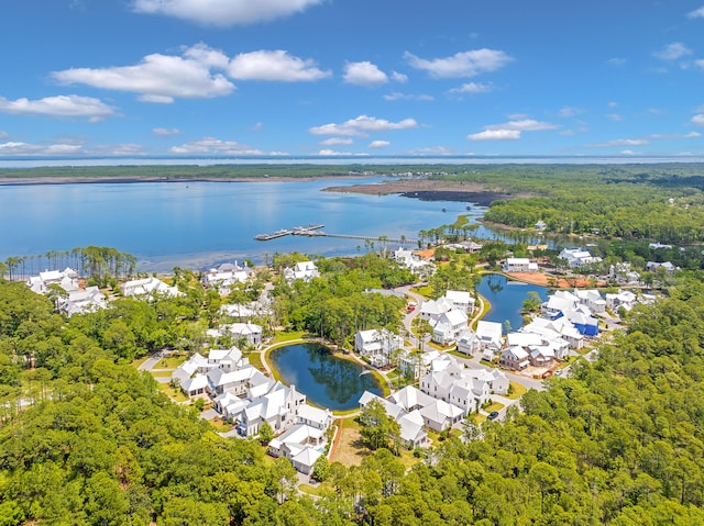 drone / aerial view featuring a wooded view, a residential view, and a water view