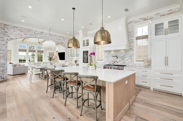 kitchen with a kitchen breakfast bar, custom range hood, a large island, and white cabinets