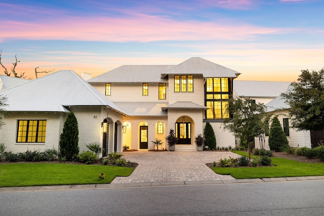 view of front of home with metal roof, a lawn, and driveway