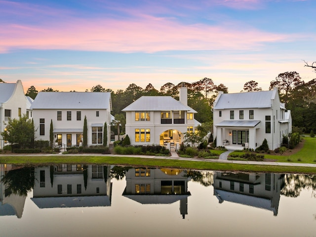 back of property at dusk featuring a water view