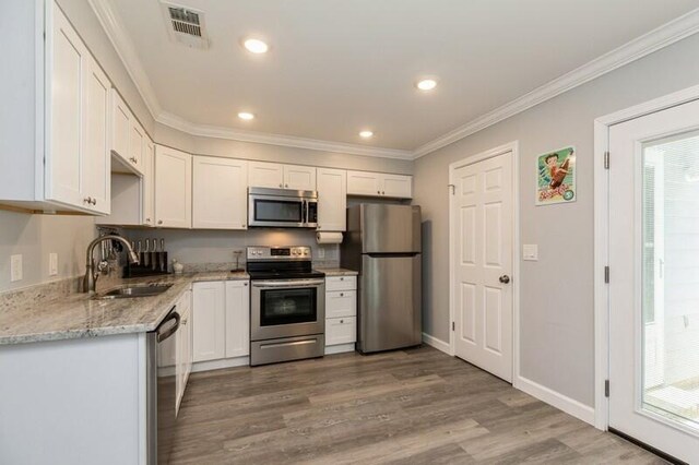 kitchen featuring stainless steel appliances, a sink, visible vents, and white cabinets