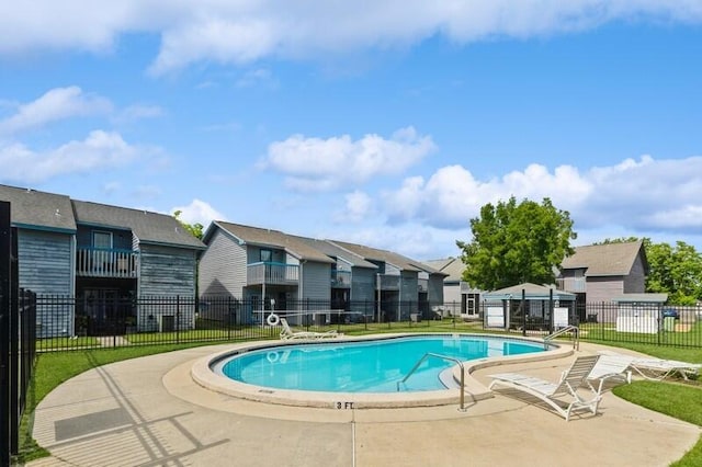 pool featuring a residential view, fence, a patio, and a yard