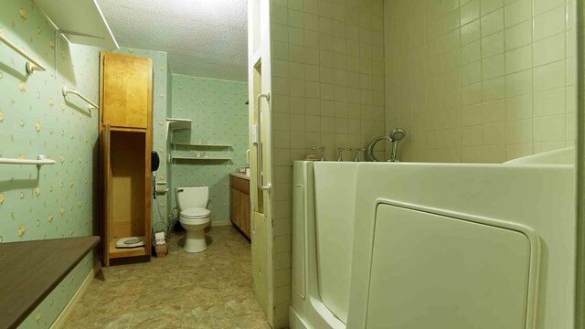 bathroom with tile patterned flooring, toilet, vanity, and a textured ceiling