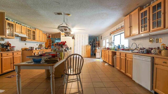 kitchen with decorative backsplash, sink, white dishwasher, a textured ceiling, and light tile patterned floors