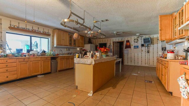 kitchen with sink, a textured ceiling, refrigerator, light tile patterned flooring, and ceiling fan