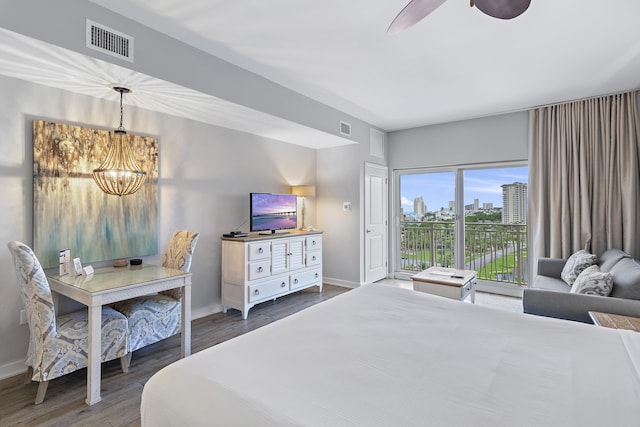 bedroom with dark hardwood / wood-style floors, ceiling fan with notable chandelier, and access to exterior