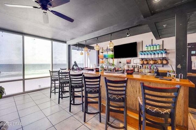 bar featuring a healthy amount of sunlight, ceiling fan, track lighting, and light tile patterned flooring