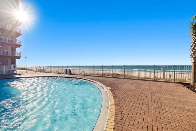 view of swimming pool featuring a view of the beach and a water view