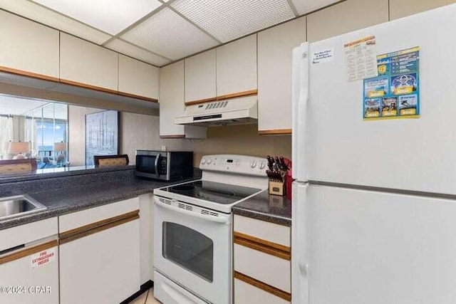 kitchen with a paneled ceiling, white appliances, and white cabinets