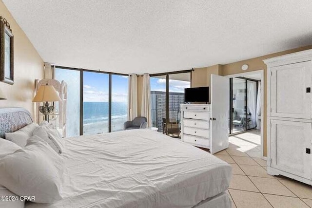 tiled bedroom featuring a textured ceiling, access to outside, and floor to ceiling windows