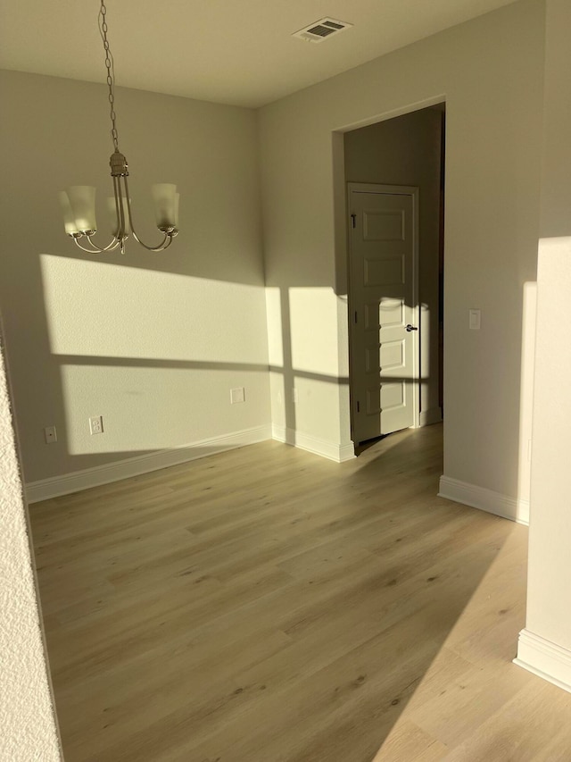 spare room featuring a notable chandelier and hardwood / wood-style flooring