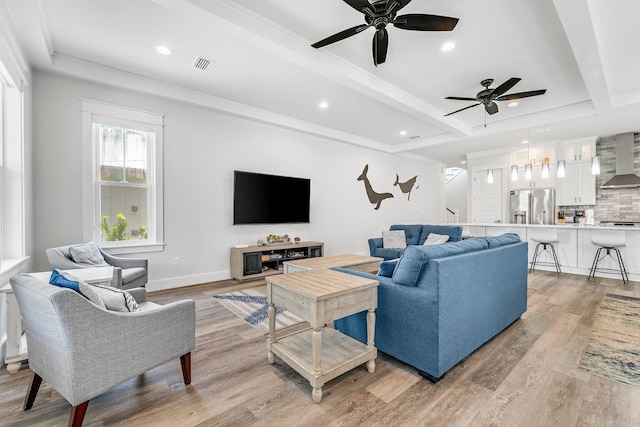 living room with light wood-type flooring, ceiling fan, crown molding, and beamed ceiling