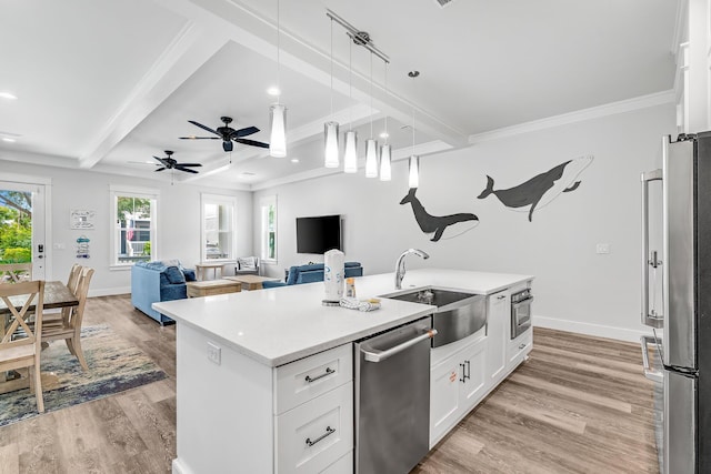 kitchen with decorative light fixtures, a center island with sink, white cabinets, appliances with stainless steel finishes, and sink