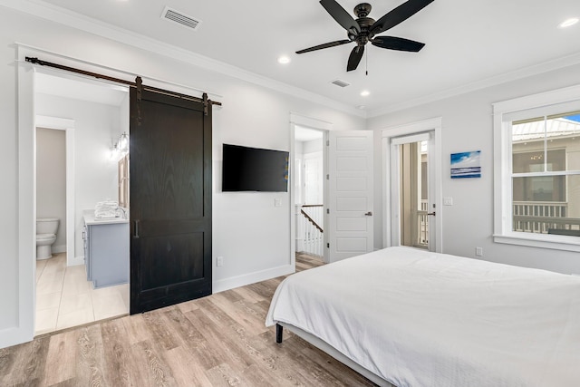 bedroom featuring light hardwood / wood-style flooring, ensuite bathroom, a barn door, crown molding, and ceiling fan