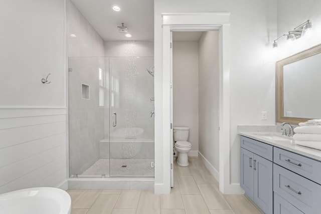 bathroom featuring a shower with door, vanity, and toilet