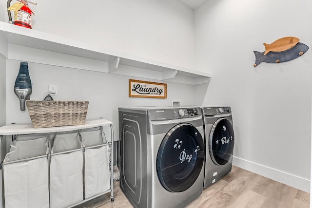 laundry room with washing machine and dryer and light hardwood / wood-style floors