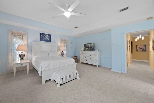 bedroom featuring a tray ceiling, light colored carpet, and ceiling fan