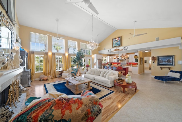 living room with high vaulted ceiling, light hardwood / wood-style floors, and ceiling fan with notable chandelier