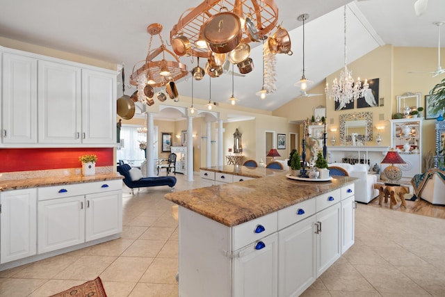 kitchen featuring ornate columns, white cabinetry, hanging light fixtures, and stone counters