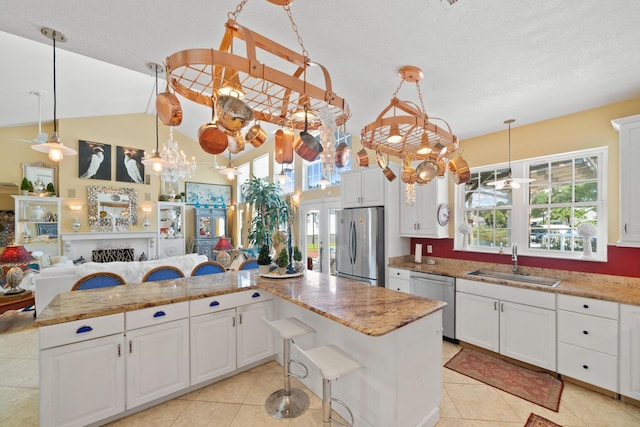 kitchen with a breakfast bar, decorative light fixtures, sink, white cabinets, and stainless steel appliances