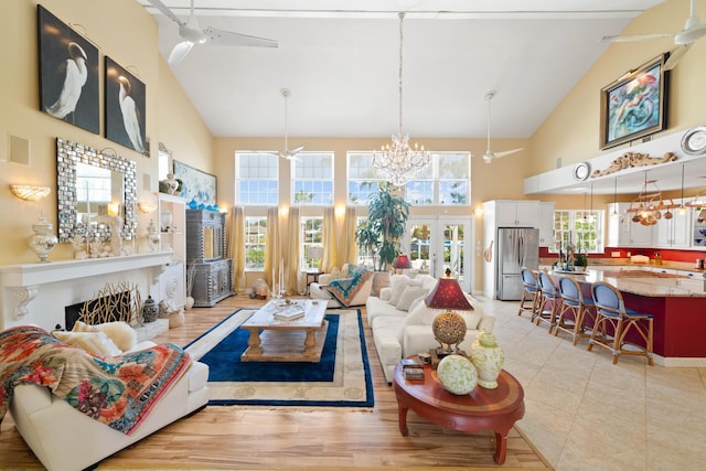 living room featuring light hardwood / wood-style flooring, ceiling fan with notable chandelier, high vaulted ceiling, and french doors