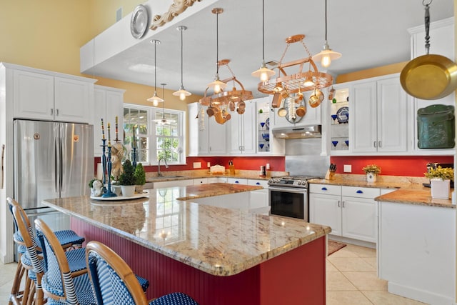 kitchen with a kitchen island, white cabinetry, appliances with stainless steel finishes, and a breakfast bar