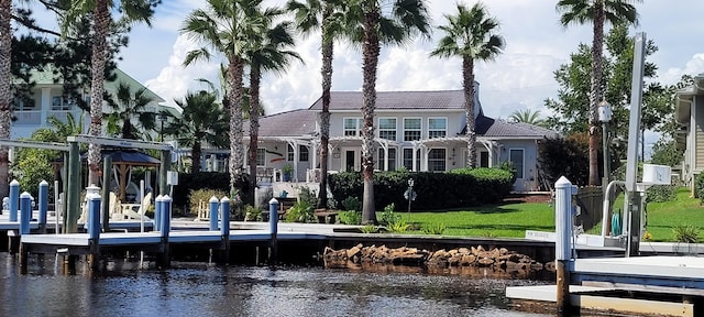 back of property with a water view, sink, and a yard