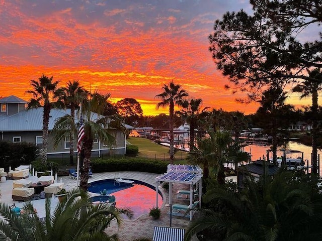 pool at dusk with a patio and a water view