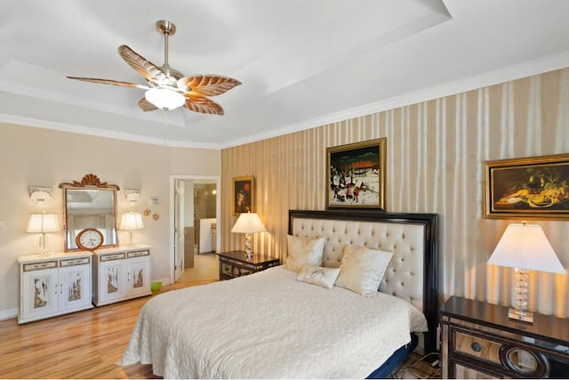 bedroom featuring crown molding, a tray ceiling, wood-type flooring, and ceiling fan