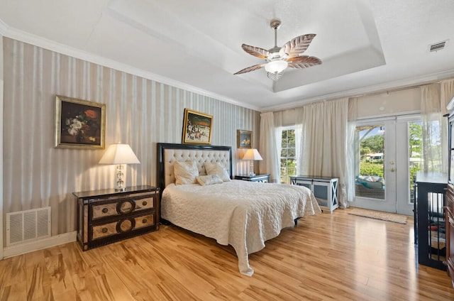 bedroom featuring hardwood / wood-style flooring, crown molding, access to exterior, and a tray ceiling