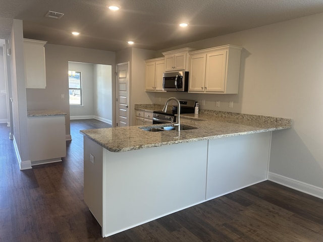 kitchen featuring stainless steel appliances, dark wood-type flooring, a peninsula, visible vents, and white cabinetry