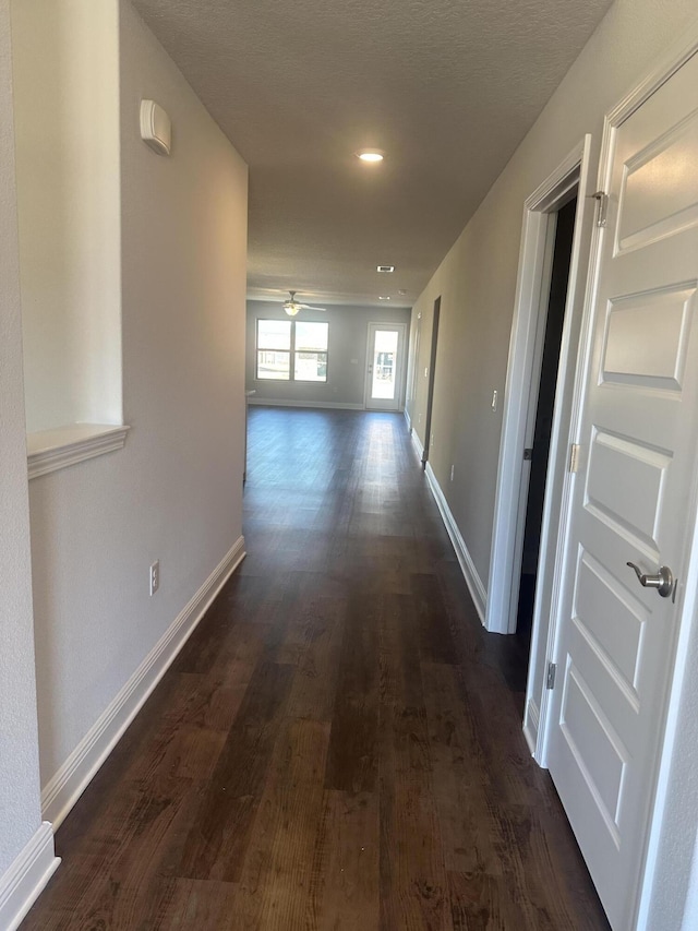 hall featuring recessed lighting, dark wood finished floors, and baseboards