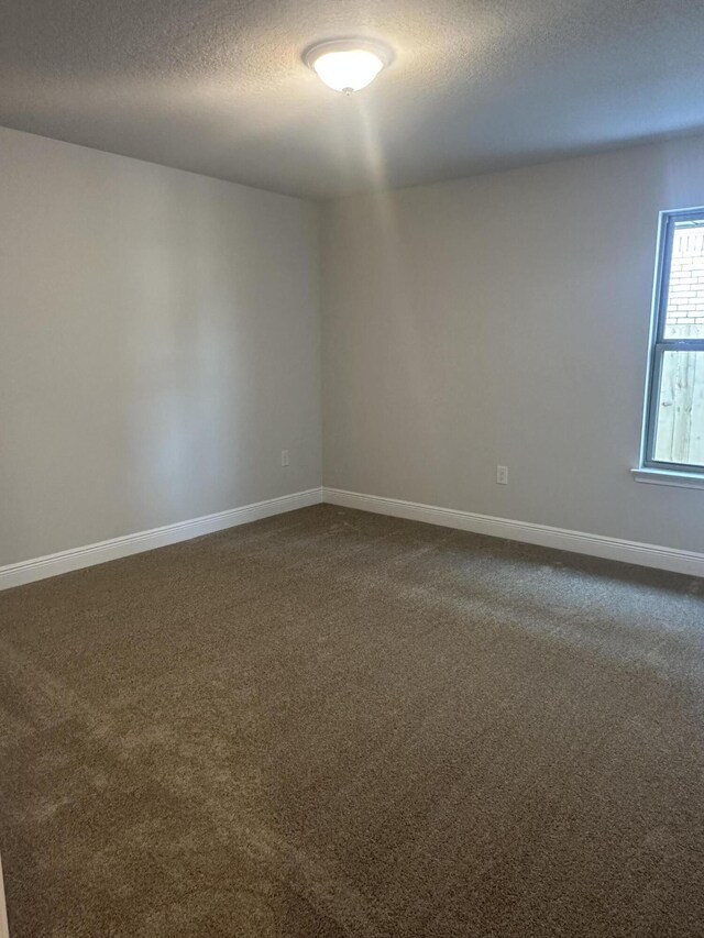 carpeted empty room with a textured ceiling and baseboards