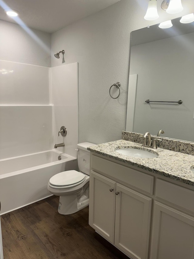 bathroom with toilet, vanity, wood finished floors, and washtub / shower combination