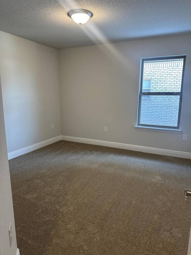 carpeted spare room with a textured ceiling and baseboards