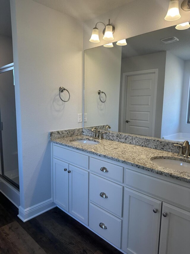 bathroom with a stall shower, a sink, baseboards, and wood finished floors