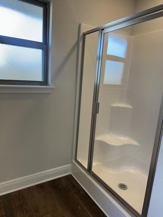 bathroom with a stall shower, wood finished floors, and baseboards