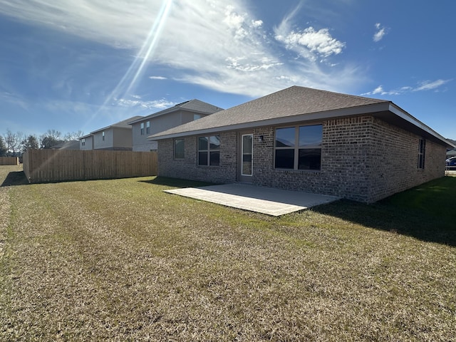 back of property featuring brick siding, a shingled roof, fence, a yard, and a patio area