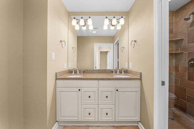 bathroom featuring tile patterned floors, tiled shower, toilet, and double sink vanity