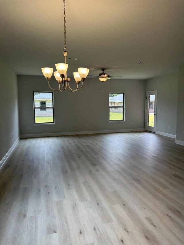 spare room with ceiling fan with notable chandelier and hardwood / wood-style floors