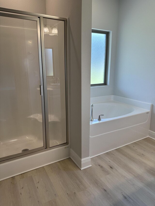 bathroom with independent shower and bath and hardwood / wood-style floors