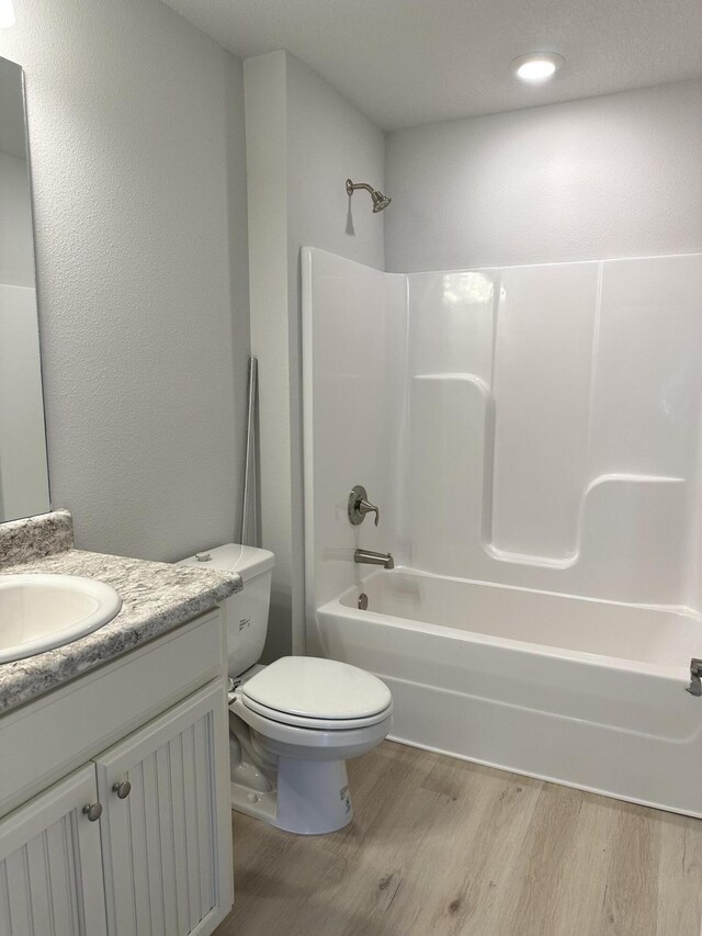 full bathroom with shower / tub combination, vanity, wood-type flooring, and toilet