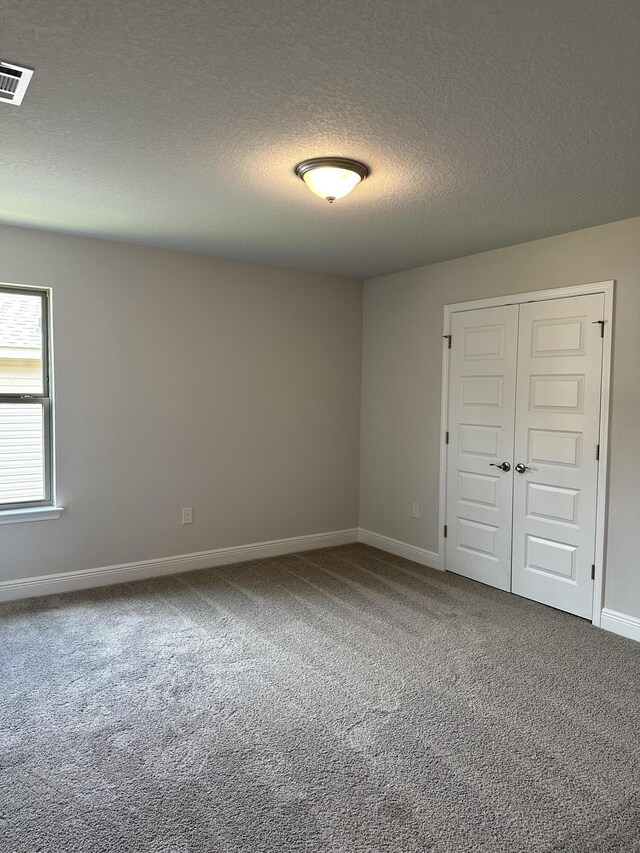 unfurnished bedroom featuring a closet, carpet, and a textured ceiling