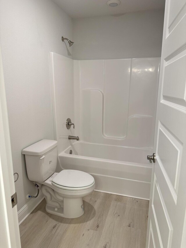 bathroom featuring toilet, hardwood / wood-style floors, and shower / bathing tub combination