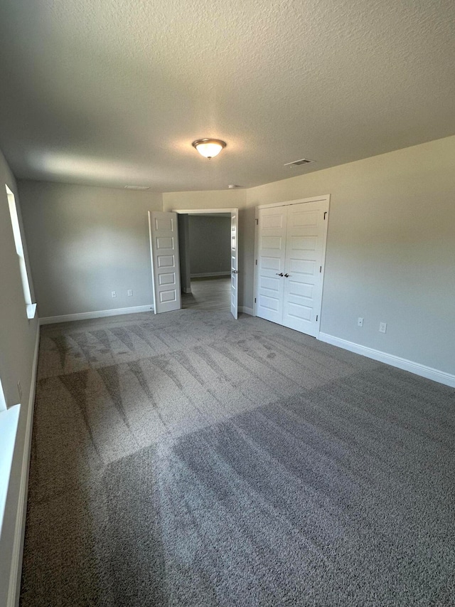 unfurnished bedroom with a closet, a textured ceiling, and dark carpet